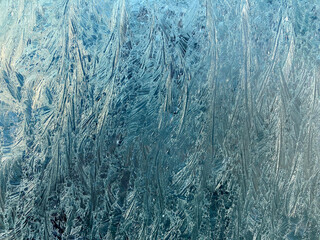 Sharp lines and swirls of ice frost on glass during winter