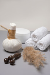Fototapeta na wymiar Spa composition of herbal massage bags, a jar of oil and a hand-held wooden massager