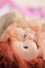 Some female dolls (plastic toys shaped as children) laying, eyes looking at the sky. Disquieting closeup shot.
