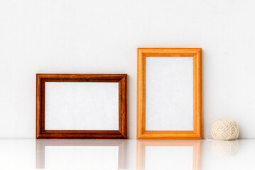Two wooden frames with a white insert inside and a tangle of light cotton threads. Photo frame on a white wall background.