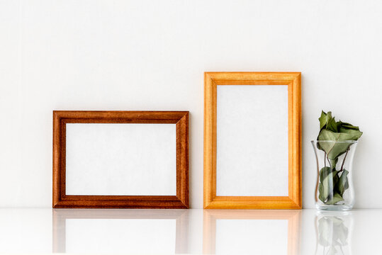 Two wooden frames with a white insert inside and a green one with a glass. Photo frame on a white wall background.