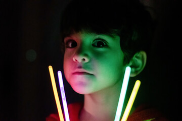 A boy playing with a glow stick in lowlight conditions