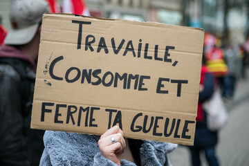 Portrait of people protesting in the street with baner with tex in french : Travaille consomme et ferme ta gueule, traduction in english : work consum and shut your mouth