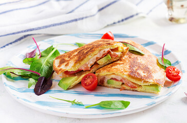 Tasty breakfast with quesadilla and eggs. Mexican cuisine. Trending food with omelet, cheese, tomatoes, avocado. Simple and easy lunch.