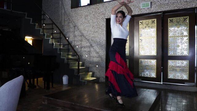 Spanish flamenco dancer dancing on a wooden stage inside a restaurant