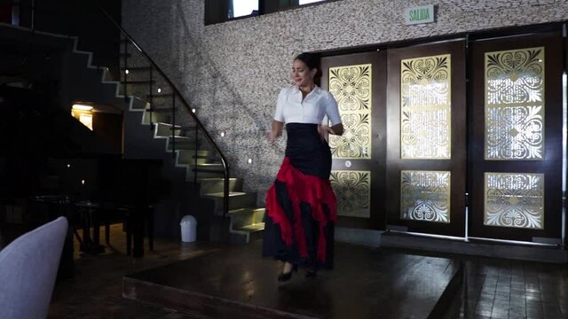Spanish flamenco dancer dancing on a wooden stage inside a restaurant