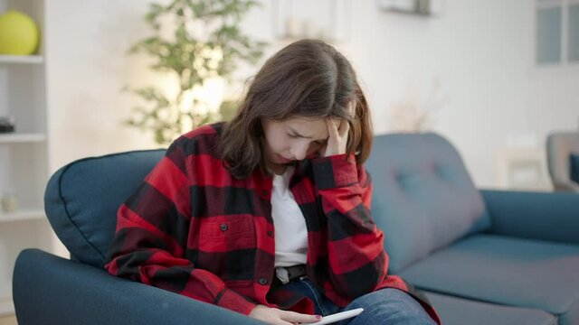 Depressed teenage girl holding positive pregnancy test, feeling shocked
