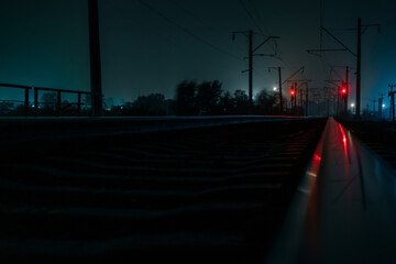 Empty railroad at night. Green traffic lights. A strong wind shakes the trees