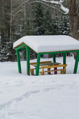 Green-painted wooden gazebo in the winter forest.