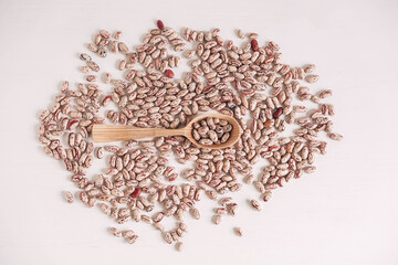 Raw dry beans in a wooden spoon scattered on a white background. Top view. Copy, empty space for text
