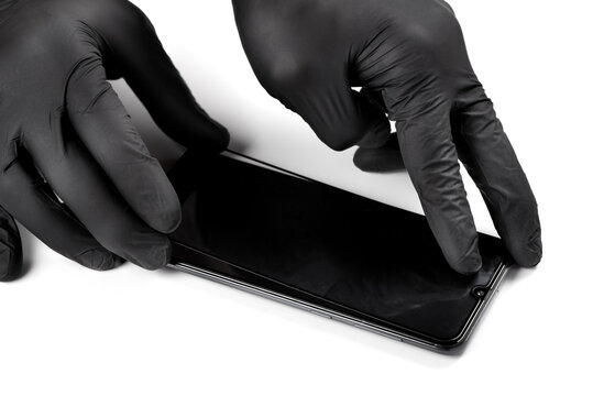 A man is installing a protective glass on the screen of a smartphone.