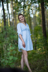 Portrait of a young beautiful girl in the forest in a light dress.