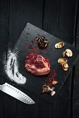Raw pickled meat beef steak with spices  on black stone background