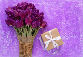 Beautiful purple tulips bouquet and gift box on a purple background. Spring flowers tulips background. Greeting card