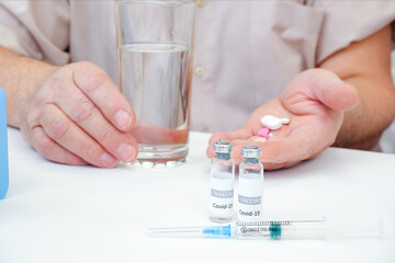Taking pills, a glass of water in the hand of an elderly person. Vaccination of an adult person in a hospital.