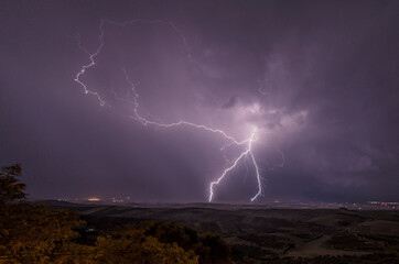 Naklejka na ściany i meble Beautiful night sky with lightning and thunderbolts during a thunderstorm in the countryside