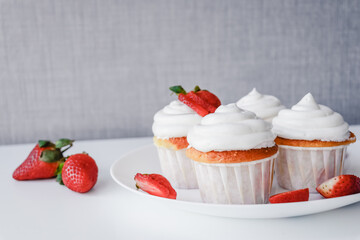 Homemade muffins with meringue caps and strawberries on a white table