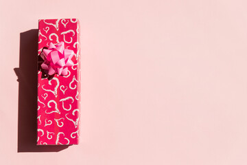 Present or gift box, paper heart and pink bow ribbon on pink background top view. Valentines day...