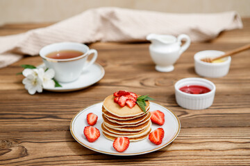 Healthy summer breakfast, homemade classic American pancakes with fresh berries and honey on a wooden background. Delicious pastries, dessert.
