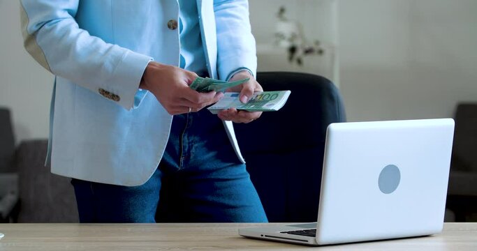 Close up of young male hands holding stack of money, fingers counting dollars banknotes. Businessman wears classic blue suit receives income, investment, salary, loan from bank, finance concept