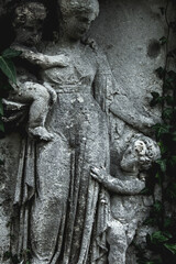 Close up an antique statue of Woman with children with description on Latin: Haritas (Сharity).