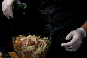 The man cut a pork neck, marinated it in spices, put it in a bowl and added olive oil to the meat,...
