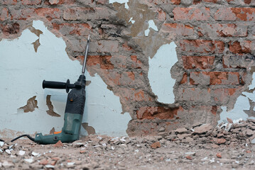 Hammer drill with chisel on the old brick wall background. Removing an old putty from the wall background.