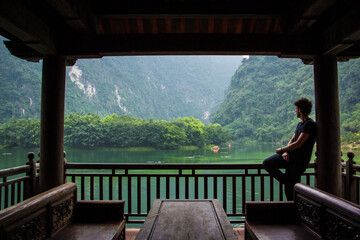 boy looking out over the lake, from wooden hut, vietnam
