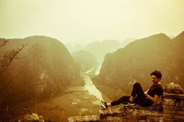 latin guy sitting on a lookout in the mountains