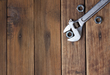 Wrench and screw-nuts on wooden planks Background