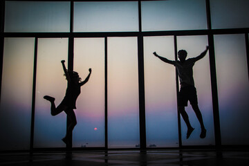 photo of silhouettes of two people jumping for joy