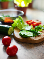 Slices of cucumber, tomatoes, spinach on a cutting board, ingredients for salad.