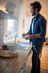 Young man enjoying doing housework in the kitchen. Kitchen, housework, quarantin, home