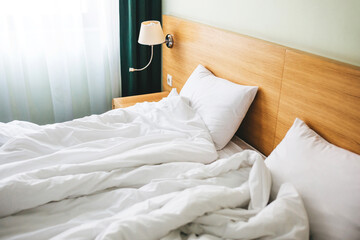 View of a rumpled bed with white pillows and a duvet.