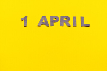 Inscription April 1 from carved letters of gray on a yellow background with copy space. High quality photo