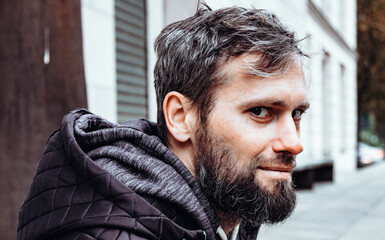 Artistic photo portrait confident smiling handsome middle-aged Caucasian man portraited in the city, with white skin, grey and black hair having a friendly look on his face, wearing a blue jacket.