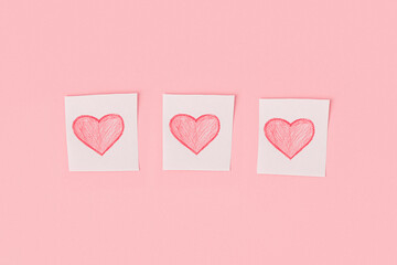 Three hearts drawn in pencil on pieces of white paper