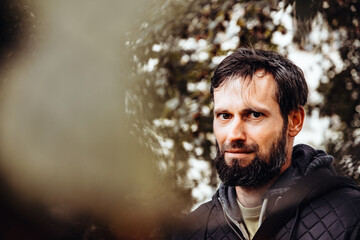Artistic photo portrait confident smiling handsome middle-aged Caucasian man portraited in the city, with white skin, grey and black hair having a friendly look on his face, wearing a blue jacket.