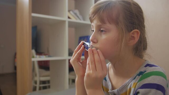 Sad girl playing harmonica home interior