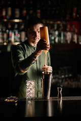 man bartender holds bottle of topping and adds it to glass of shaker
