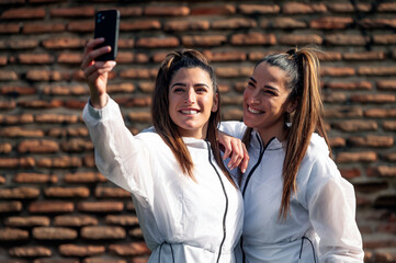 Two beautiful twin sisters taking a selfie photo with cell phone
