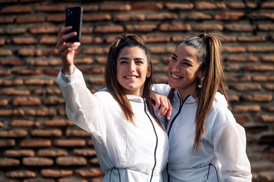 Two beautiful twin sisters taking a selfie photo with cell phone