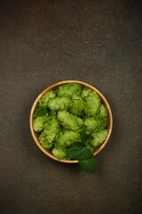 Wooden bowl of fresh green hops on table