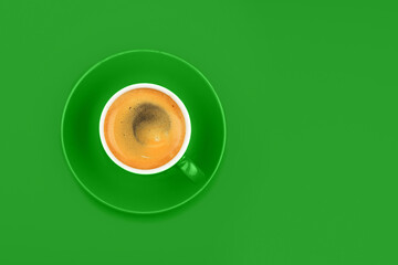 One full espresso coffee cup with saucer on green