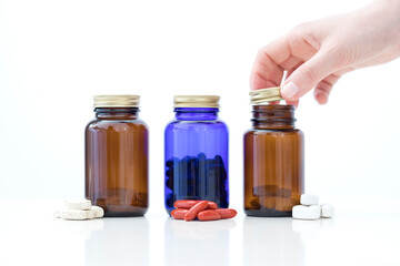 Closeup image of three pill bottles with one hand open one of them.