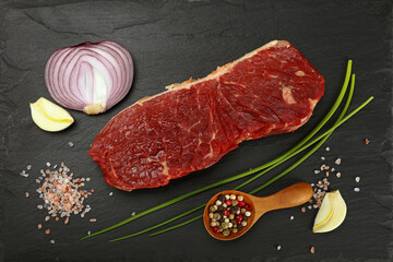 Raw beef steak meat cut and spices on black board