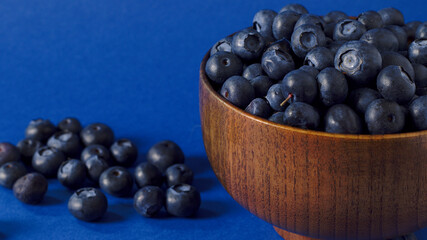 Arándanos en un bol de madera sobre fondo marrón rústico