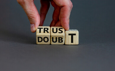 Trust or doubt symbol. Businessman flips wooden cubes and changes the word doubt to trust. Beautiful grey background, copy space. Business and trust or doubt concept.