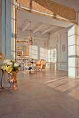 rich apartment interior with golden baroque decorations on the walls and luxury furniture. the room is flooded with the rays of the setting sun