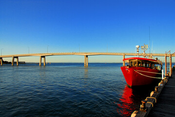 Fototapeta na wymiar Red Fishing Boat in the Late Afternoon Sun In San Remo, Victoria, Australia.